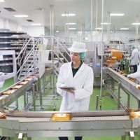 Quality control worker with digital tablet at production line in cheese processing plant
